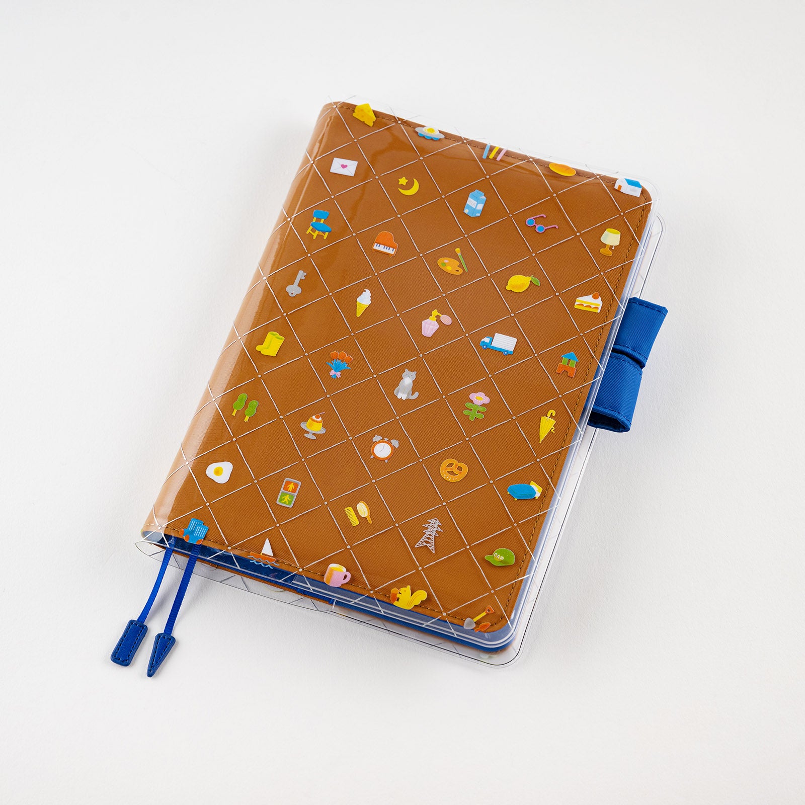 Hobonichi Kanako Kagaya: Cover on Cover for A5 Size (Familiar Sights) Cover on cover is a protective cover that can be used on top of your Hobonichi Cousin cloth covers to protect them from wear and tear. This product can not be used on top of the book only. You can also store illustrations under your cover on cover to boost your Hobonichi covers design. The design for “Familiar Sights” was created by designer and illustrator Kanako Kagaya.