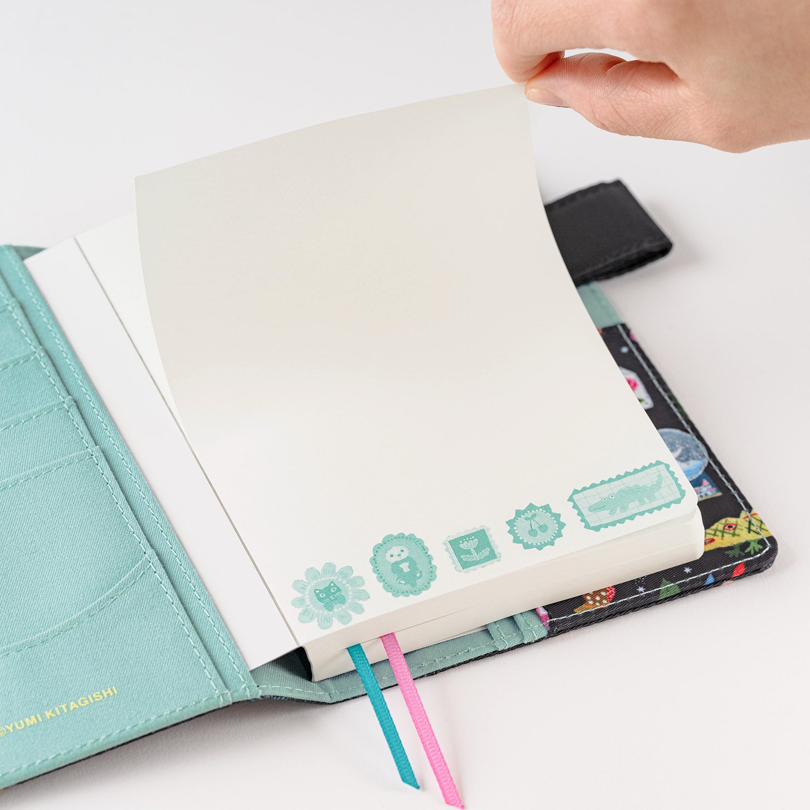Hobonichi Yumi Kitagishi: Hobonichi Paper(s) Notebook (Take a Look) This A6 notepad has 155 pages. The paper inside is blank except for a lightly printed illustration, and the pages are glued in instead of sewn, making them very easy to rip out for shopping lists or passing along messages. The cover artwork is by illustrator Yumi Kitagishi titled Take a Look.